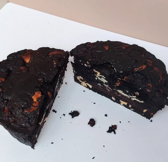 Dark chocolate cake with a slice cut out on a white surface