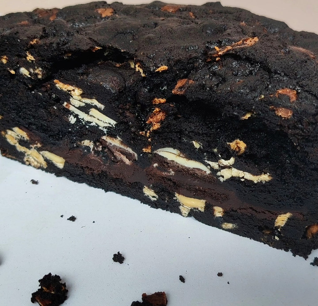 Close-up of a dark chocolate brownie with white chocolate chips on a light blue background