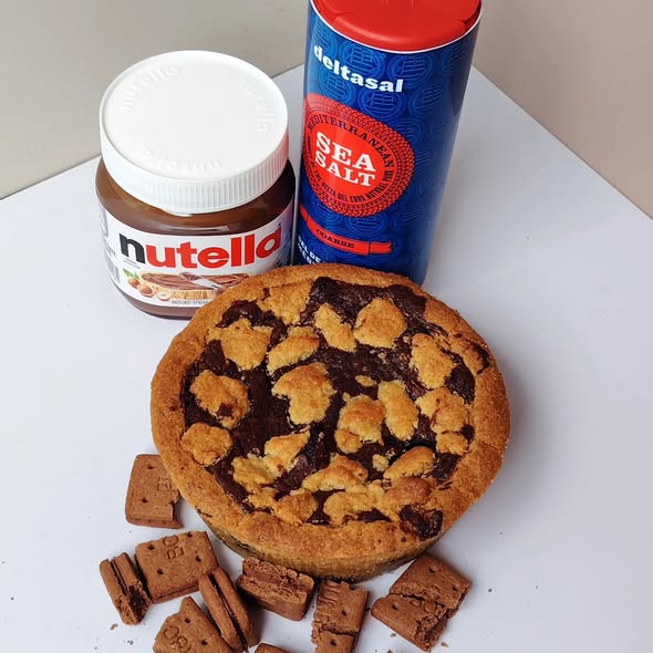 Singapore halal Cookie with chocolate pie  pieces, Nutella jar, and sea salt container on a white surface