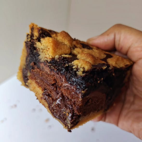Singapore halal Hand holding a slice of brownie chocolate pie  cake with a light brown crust.