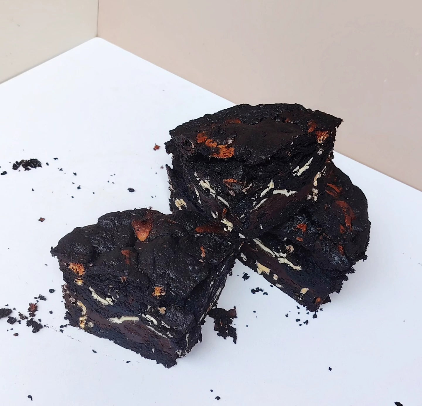 Stack of dark chocolate brownies on a white surface with a beige background