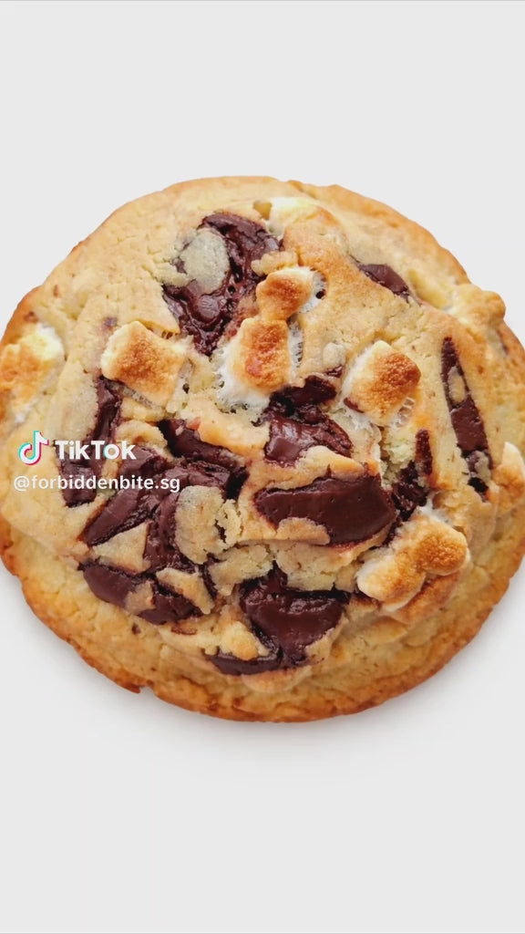 Our S’mores Choc Chunk Cookie is baked chunky and golden, packed with rich chocolate chunks, and topped with toasted mini marshmallows that caramelise beautifully in the oven. The edges come out crisp, the centre stays soft and buttery, and every bite gives you melty chocolate + gooey marshmallow goodness — minus the tent.