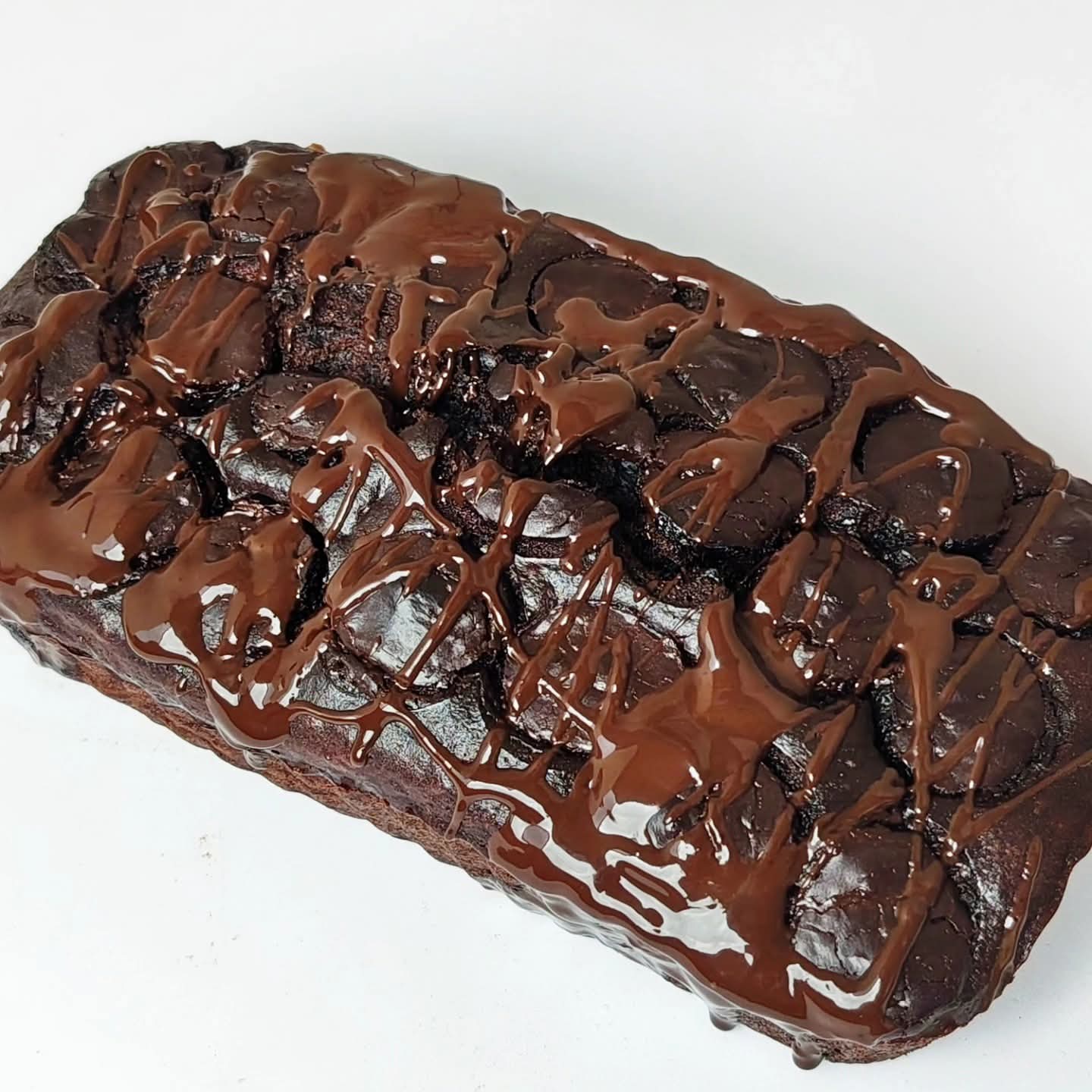 Singapore halal moist banana Chocolate cake with a glossy chocolate glaze on a white background
